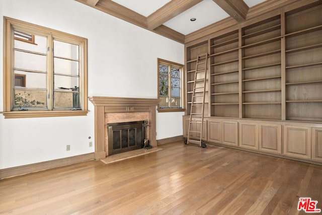 unfurnished living room featuring hardwood / wood-style floors, beam ceiling, coffered ceiling, a high end fireplace, and built in shelves