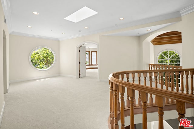 hall with crown molding, light colored carpet, and a skylight