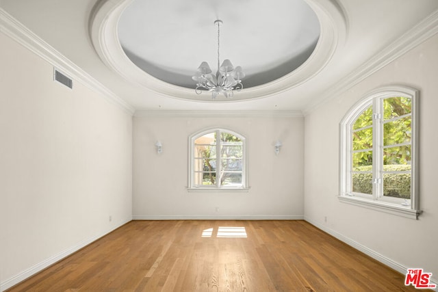 unfurnished room featuring ornamental molding, a tray ceiling, a chandelier, and hardwood / wood-style floors