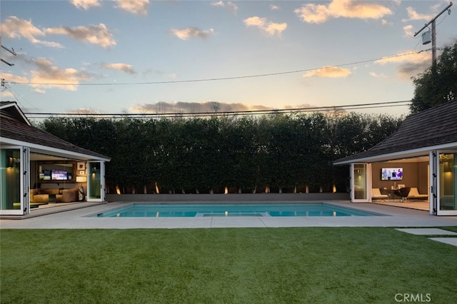 pool at dusk featuring a lawn