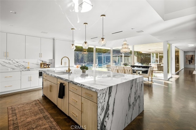 kitchen featuring light stone countertops, tasteful backsplash, a large island, white cabinets, and light brown cabinets