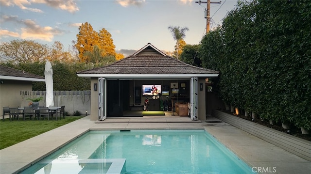 pool at dusk featuring an outbuilding and a patio