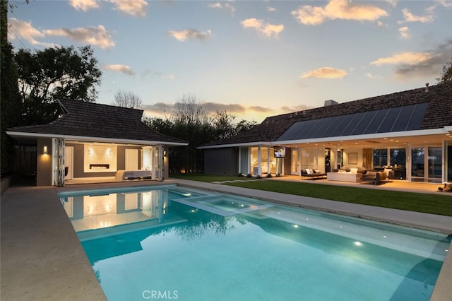 pool at dusk with a patio, an outbuilding, and outdoor lounge area