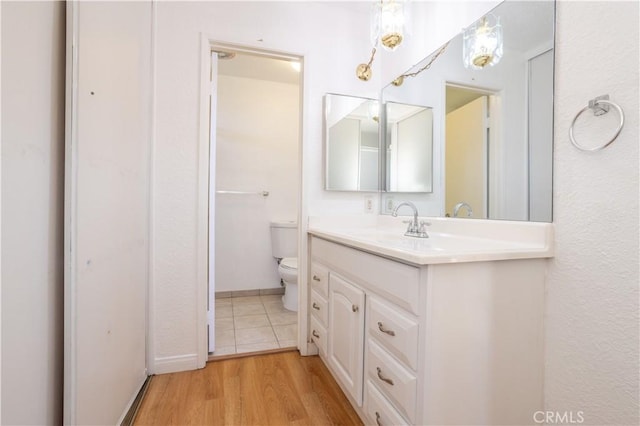 bathroom with wood-type flooring, toilet, and vanity