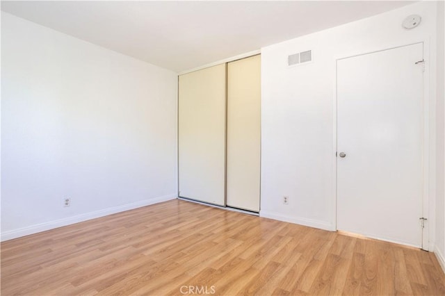 unfurnished bedroom featuring light hardwood / wood-style flooring and a closet