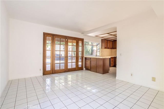 interior space with sink, french doors, kitchen peninsula, and light tile patterned flooring