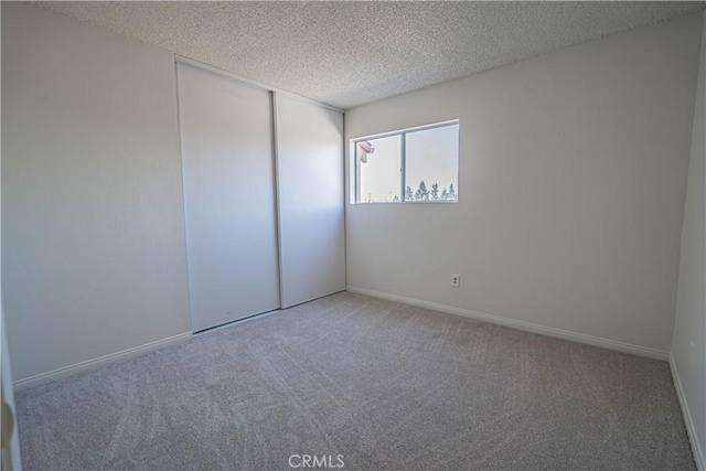 unfurnished room with a textured ceiling and carpet flooring