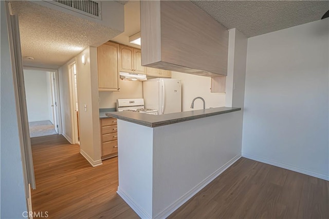 kitchen featuring white appliances, a textured ceiling, sink, dark hardwood / wood-style floors, and kitchen peninsula