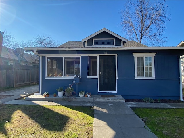 bungalow with a sunroom, a front lawn, and fence