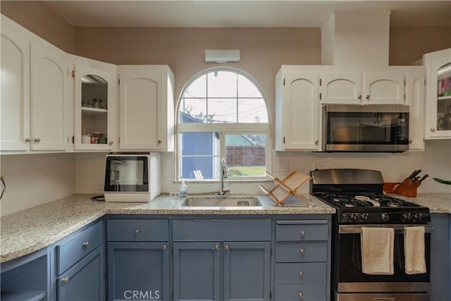 kitchen featuring a sink, white cabinetry, appliances with stainless steel finishes, and glass insert cabinets