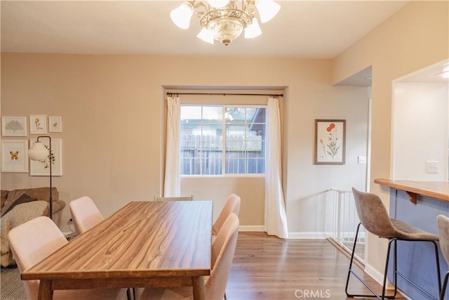 dining room with baseboards, wood finished floors, and a notable chandelier