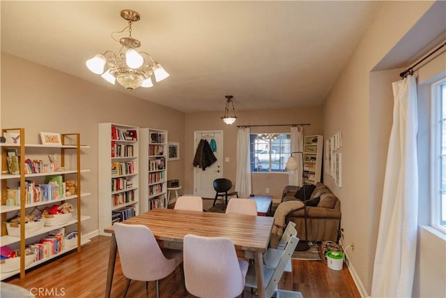 dining space with dark wood-type flooring, baseboards, a chandelier, and a wealth of natural light