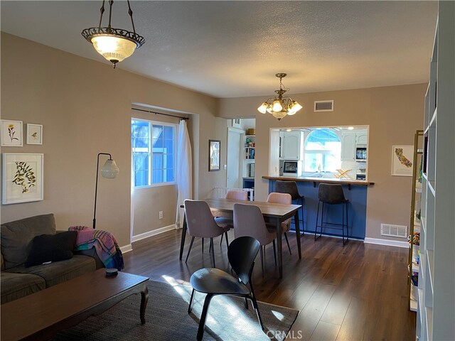 dining area with baseboards, dark wood-type flooring, a chandelier, and visible vents