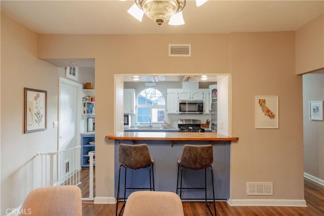 kitchen featuring visible vents, appliances with stainless steel finishes, wood finished floors, and ceiling fan