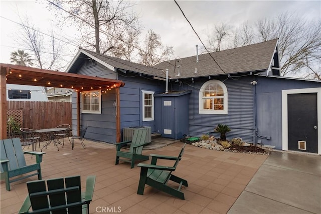 back of property featuring fence, a shingled roof, central AC unit, outdoor dining area, and a patio area