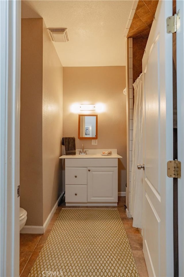 bathroom featuring visible vents, baseboards, toilet, and vanity