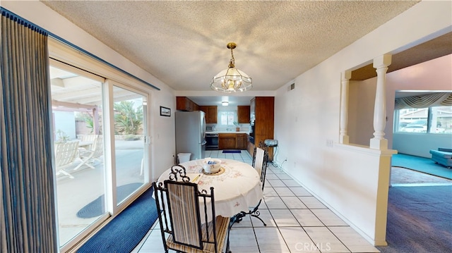 dining room with a chandelier, a textured ceiling, and light tile patterned flooring