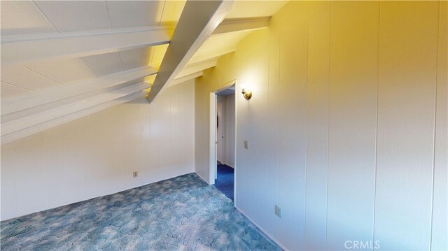 bonus room featuring wooden walls, lofted ceiling with beams, and dark colored carpet