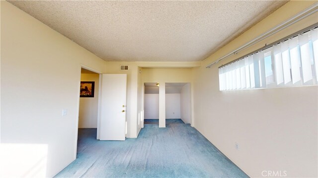 carpeted empty room with a textured ceiling