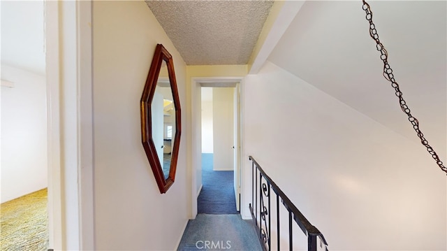 hallway with carpet and a textured ceiling