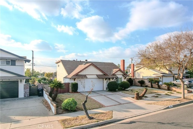 view of front facade with a residential view, concrete driveway, and fence