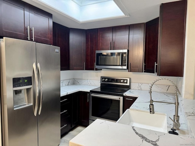 kitchen featuring light stone counters, sink, and appliances with stainless steel finishes