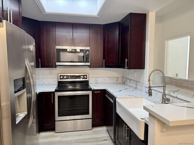 kitchen featuring appliances with stainless steel finishes, light stone countertops, and sink