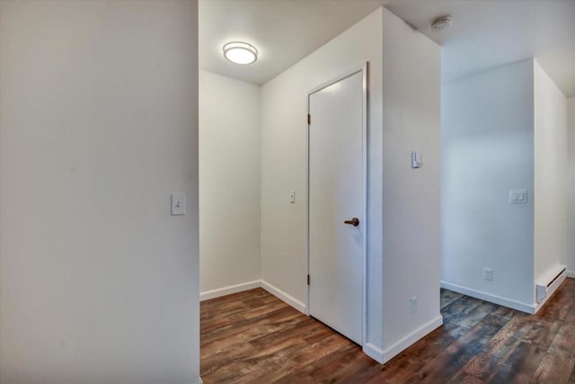 hallway with a baseboard heating unit and dark hardwood / wood-style floors