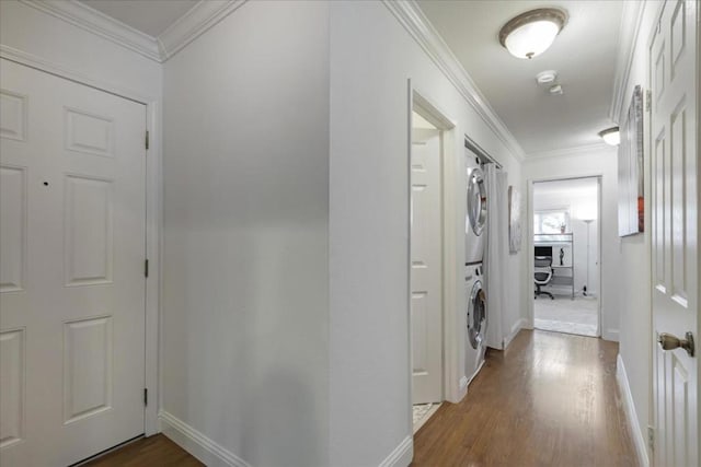 hall featuring stacked washer / dryer, hardwood / wood-style flooring, and ornamental molding