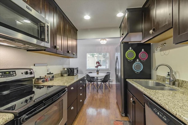 kitchen with light hardwood / wood-style floors, sink, appliances with stainless steel finishes, and dark brown cabinets