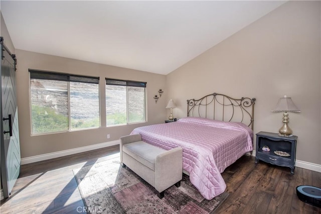 bedroom featuring dark wood-type flooring, a barn door, and vaulted ceiling