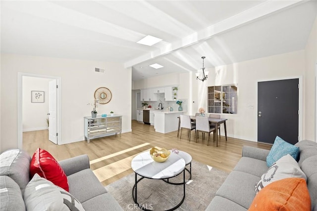 living room with sink, light wood-type flooring, lofted ceiling with beams, and a notable chandelier