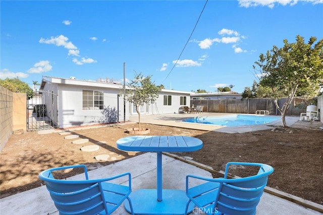 rear view of property with a fenced in pool and a patio