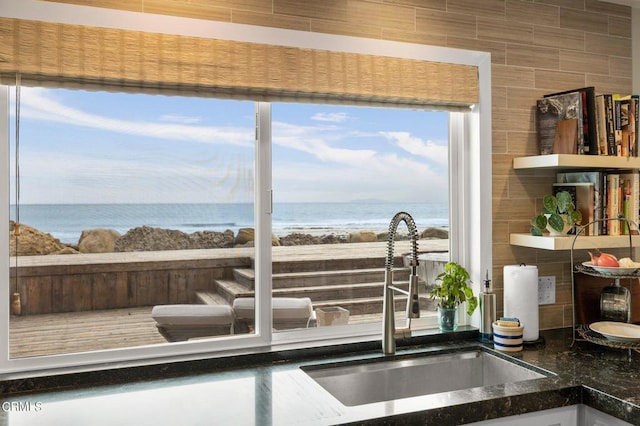 doorway to outside featuring sink, a water view, and tile walls