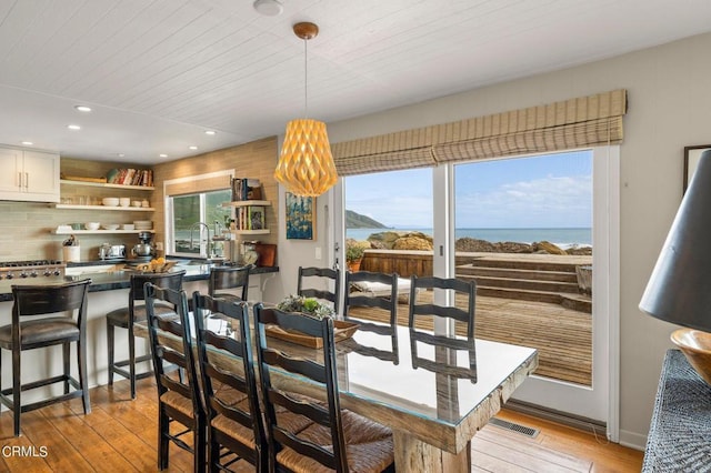 dining area with wood ceiling, light hardwood / wood-style floors, a wealth of natural light, and a water view