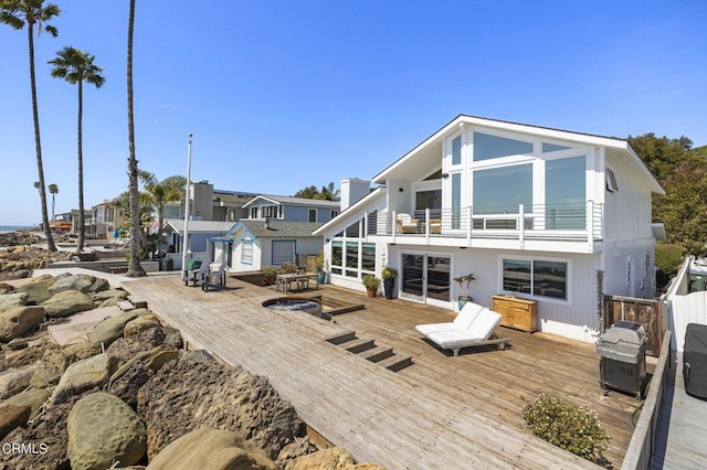 back of property featuring a balcony and a wooden deck