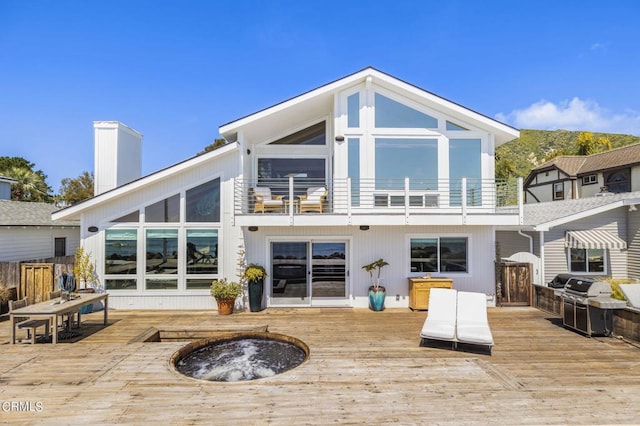 back of property featuring a balcony and a deck