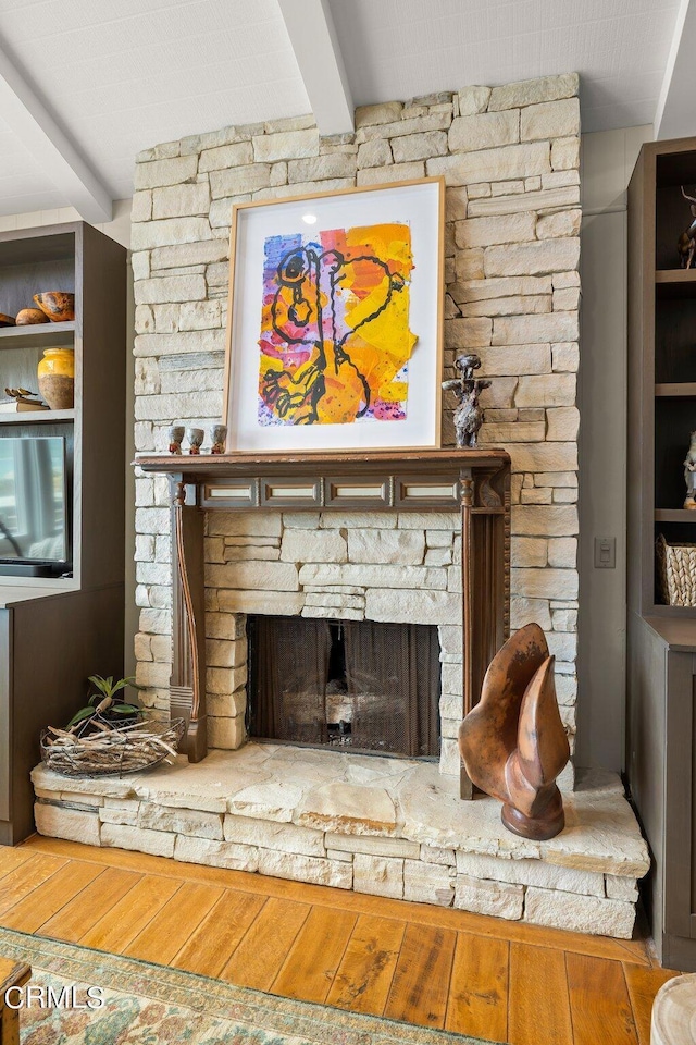 room details with beamed ceiling, hardwood / wood-style floors, and a fireplace