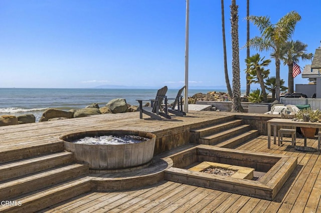 wooden deck featuring a fire pit and a water view