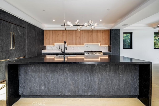 kitchen featuring decorative light fixtures, sink, decorative backsplash, and stove