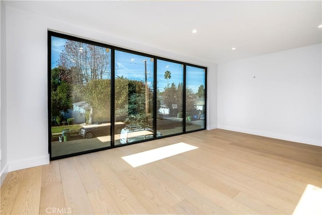 empty room featuring light wood-type flooring and a wall of windows