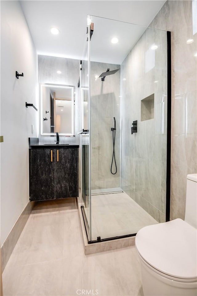 bathroom featuring vanity, toilet, and a shower with door