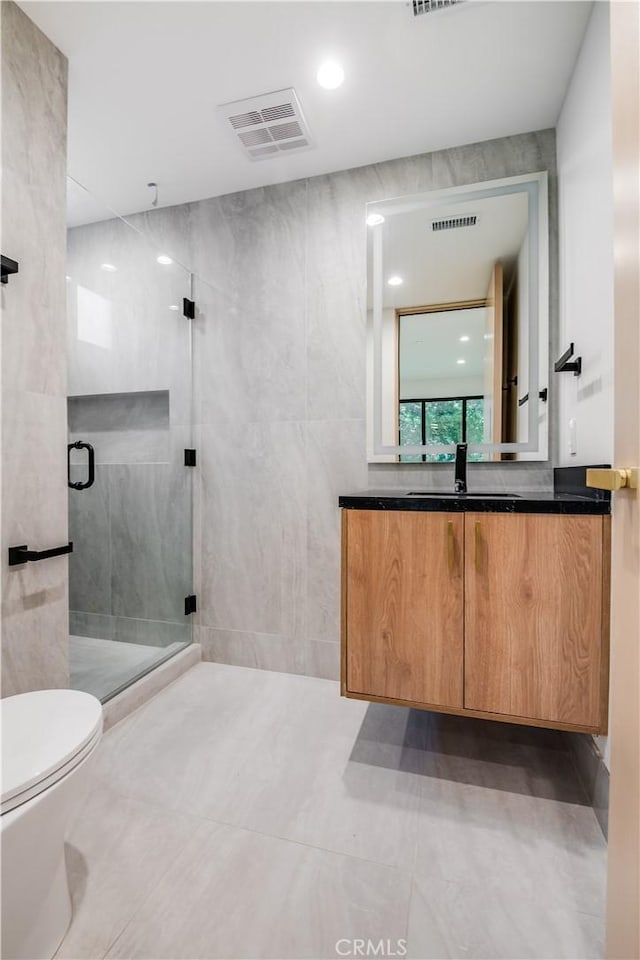 bathroom featuring tile walls, toilet, vanity, and an enclosed shower