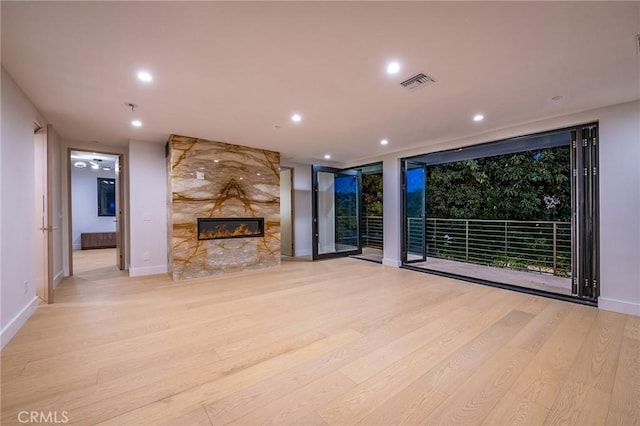 unfurnished living room with light wood-type flooring and a high end fireplace