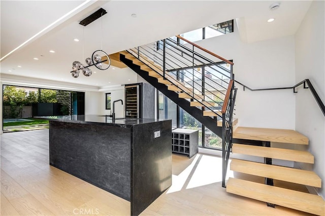 interior space with pendant lighting, an inviting chandelier, dark stone countertops, sink, and light hardwood / wood-style flooring