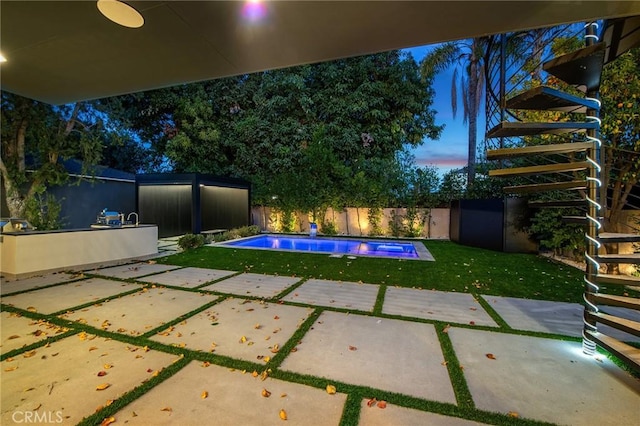 pool at dusk with a lawn and a patio