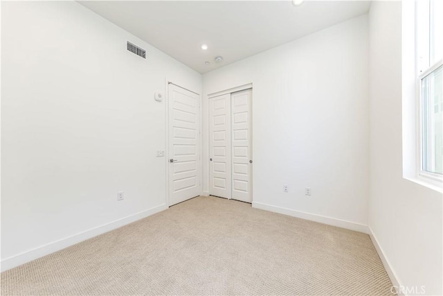 unfurnished bedroom featuring visible vents, baseboards, light colored carpet, recessed lighting, and a closet