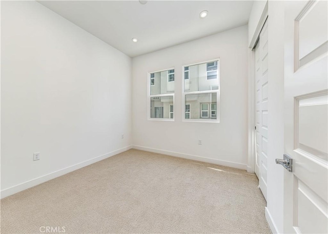 spare room featuring recessed lighting, baseboards, and light carpet