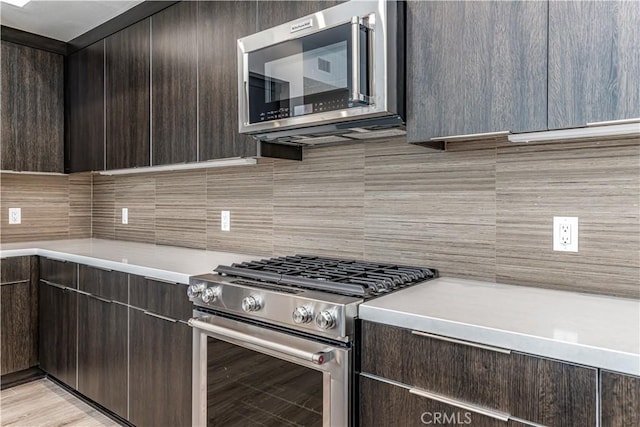 kitchen with backsplash, dark brown cabinetry, light countertops, stainless steel appliances, and modern cabinets