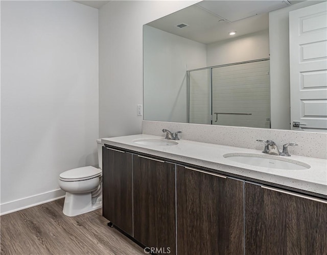 full bath featuring a shower stall, toilet, wood finished floors, and a sink